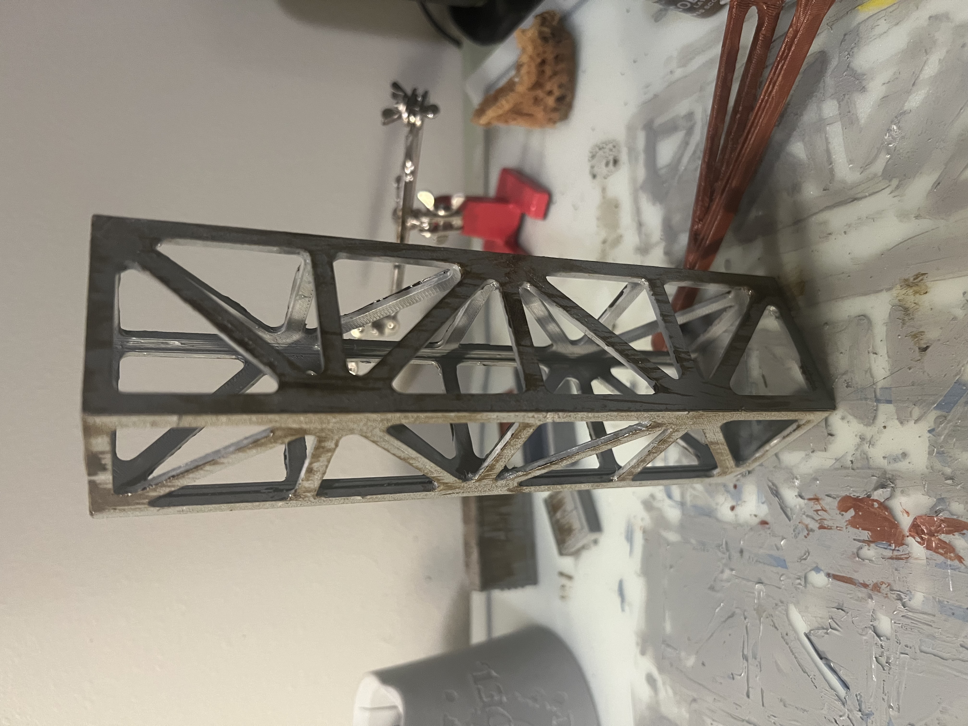 The assembled truss painted gray with brown rust streaks running down it.