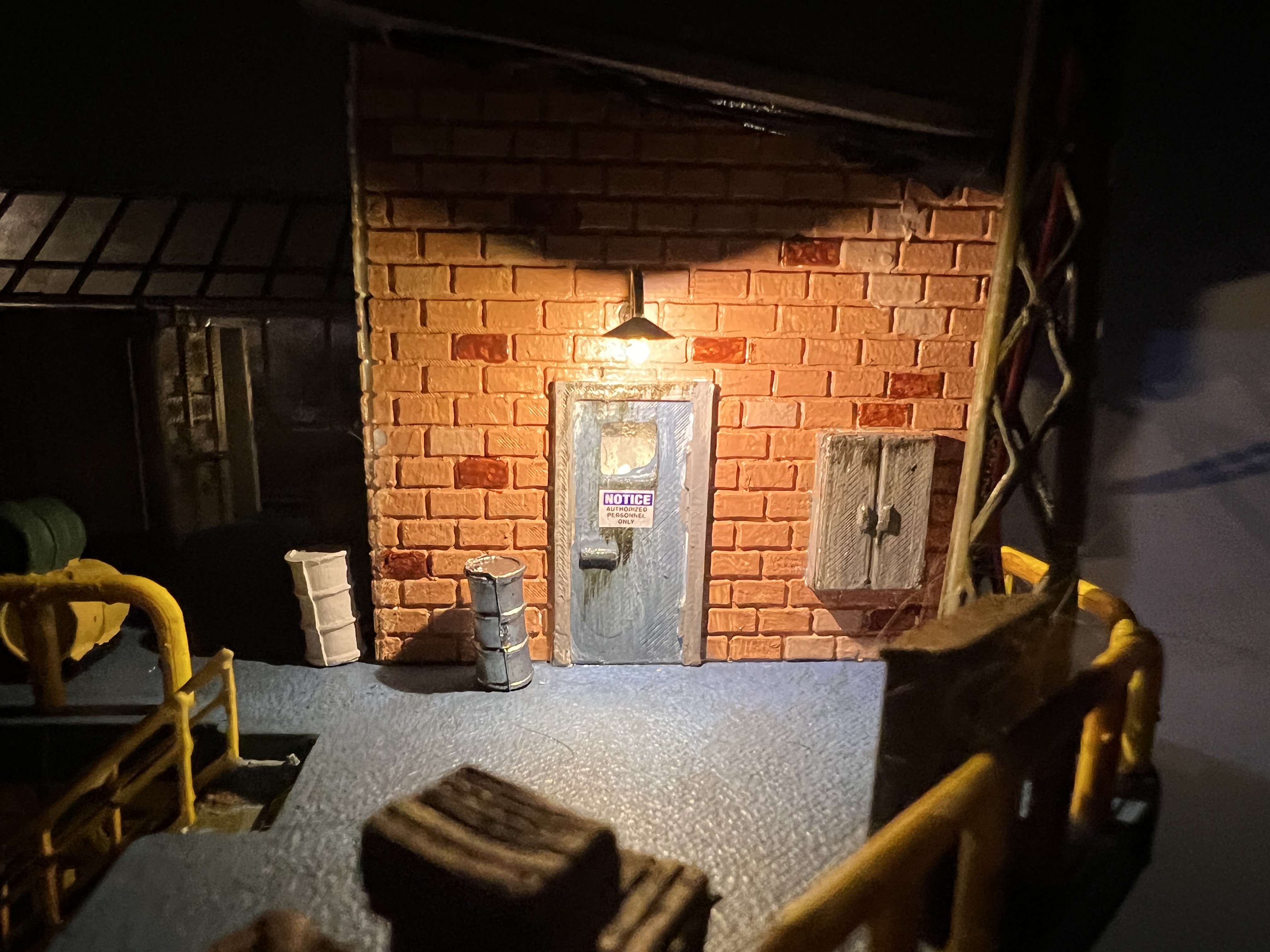 A small shed on the rig at night, with a miniature notice sign posted beside the door.